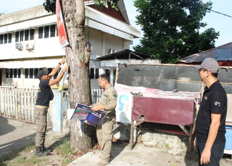 Panwaslih Kota Lhokseumawe bersama Satpol PP kembali menertibkan alat peraga kampanye (APK) yang melanggar aturan di kawasan militer lokasi perkantoran TNI/Polri di Jalan Iskandar Muda, Lhokseumawe. Foto: Ist